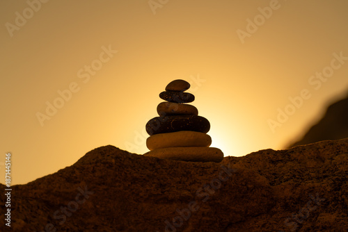 Foto Balance cairn silhouette stacks stones against a vibrant golden sunset sky, symbolizing meditation and tranquility