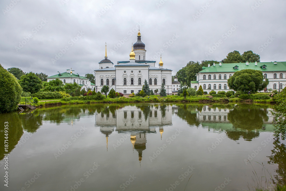 Fototapeta premium Monastery grounds with a pond and a view of the Cathedral of the Three Holy Hierarchs. Spaso-Eleazarovsky Convent. Elizarovo village, Pskov Oblast, Russia