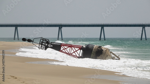 Grande bouée de navigation maritime rouge et noire échouée sur une plage de sable