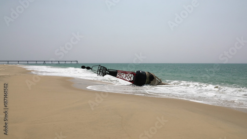 Grande bouée de navigation maritime rouge et noire échouée sur une plage de sable