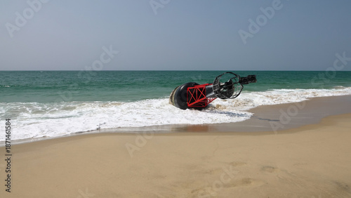 Grande bouée de navigation maritime rouge et noire échouée sur une plage de sable