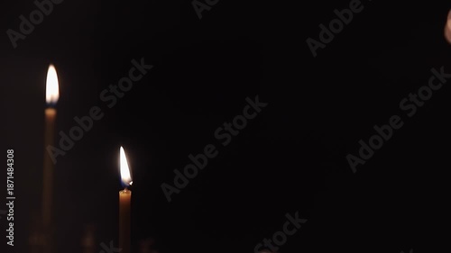 Candle flames flicker gently in a dimly lit space, highlighting the interplay of light and shadow, enhancing the tranquil ambiance and visual depth of the scene