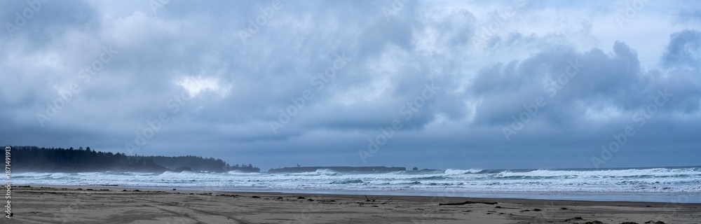 Fototapeta premium Panorama of stormy skies over Coos Head Beach with the Point Arago lighthouse in the distance near Charleston, Oregon, USA