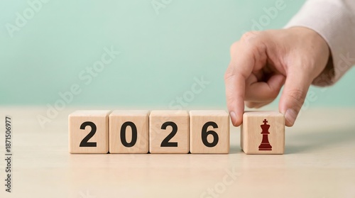 Hand placing chess queen on 2026 wooden blocks, strategy concept