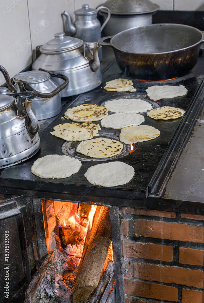 Naklejka premium Traditional Costa Rican cuisine of tortillas cooking on old cast iron wood fired stove