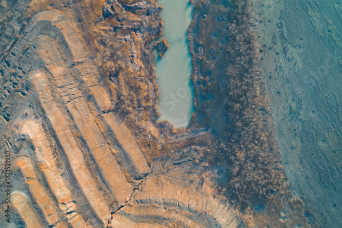 Clay quarry terrain and industrial water pool, scarred earth surface texture, environmental digging concept, aerial drone shot top view