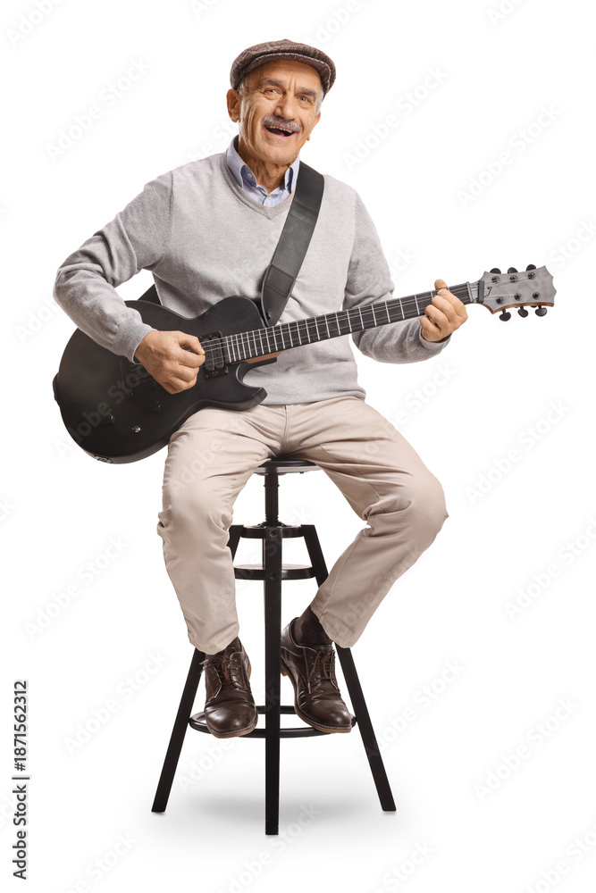 Obraz premium Happy senior man sitting on a stool and playing an electric guitar