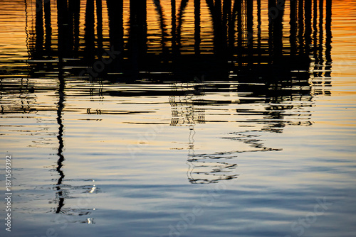 A colorful abstract depiction of the silhouette of a dock against the sunset, reflected in the water in the fishing village of Lubec, Maine