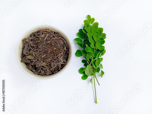Dry Moringa leaf tea or kelor in a small bowl, isolated on a white background, herbal drink, healthy lifestyle