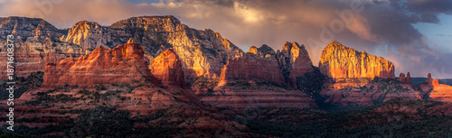 Panoramic view of glowing red rock mountains against a dramatic dark stormy sky in Sedona, Arizona