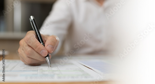 Business professional reviewing and signing financial documents with pen on desk. Corporate paperwork, audit process, accounting review, compliance, administration, and professional business workflow 