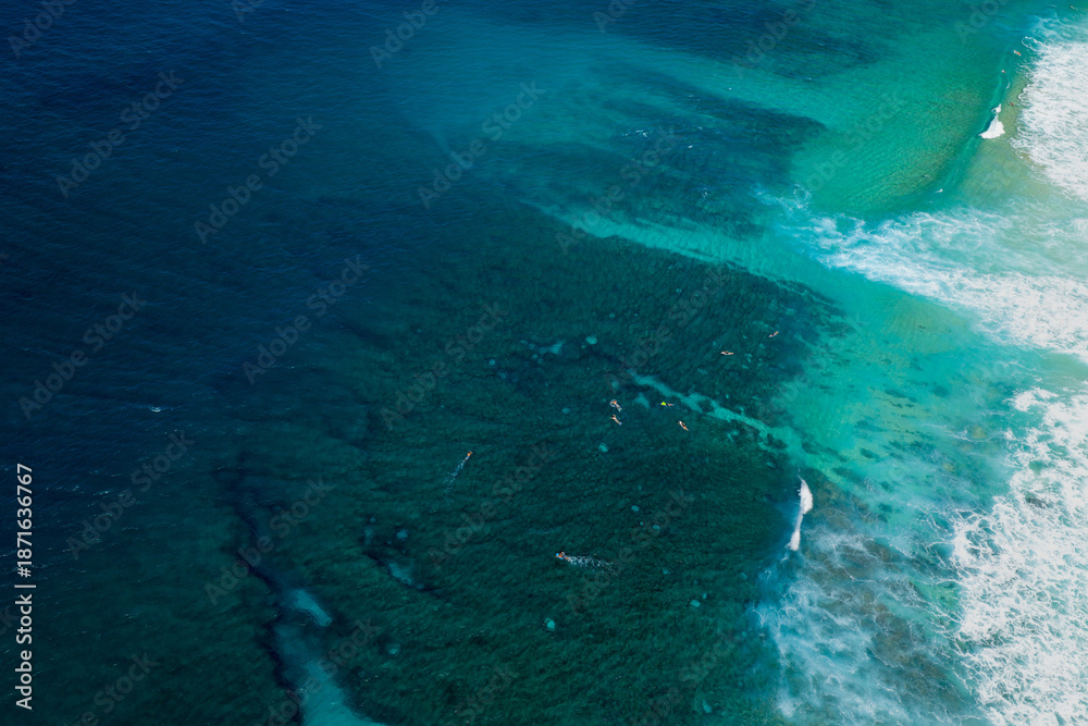 Fototapeta premium Aerial view of reef patterns visible through clear turquoise water at Banzai Pipeline on the North Shore of Hawaii, showing underwater textures and tropical coastline detail.