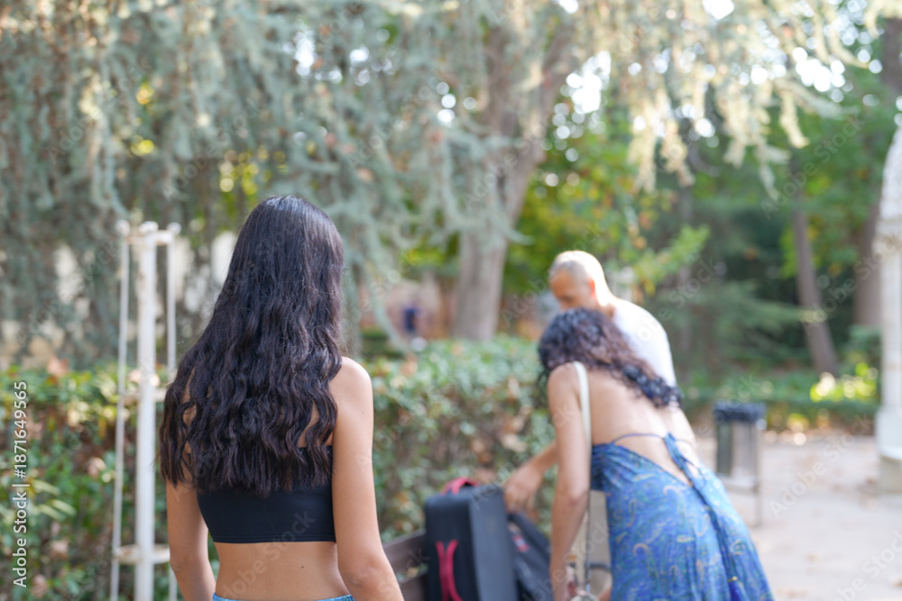 Fototapeta premium A woman in a black tank top is walking past a man in a white shirt. The woman is wearing a blue dress