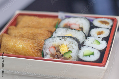 Top down view of a box of obento or lunch box with California rolls and Inari sushi or fried tofu pouch sushi - Japanese cuisine