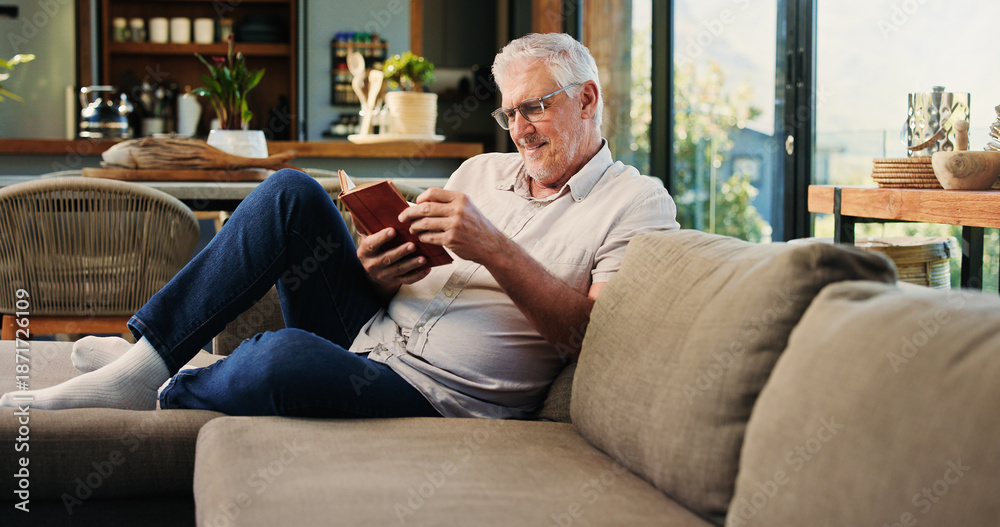 Fototapeta premium Reading, book and mature man on sofa with smile, calm and literature hobby on weekend rest. Free time, study and senior person in house with novel, relax and fantasy story on Saturday afternoon.