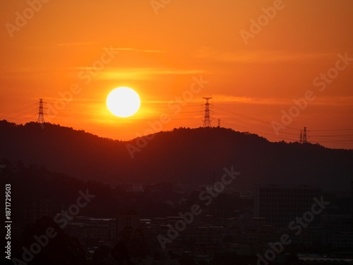 sunset over the mountain range and cityscape in dark