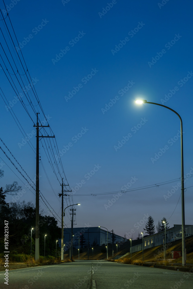 Obraz premium 夕暮れの空を背景にした街灯と送電線の風景