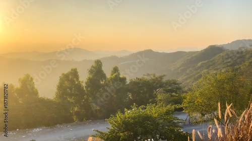 Stunning Golden Sunset Over the Rolling Mountains, Scenic Nature Background with Sun Flare and Green Trees