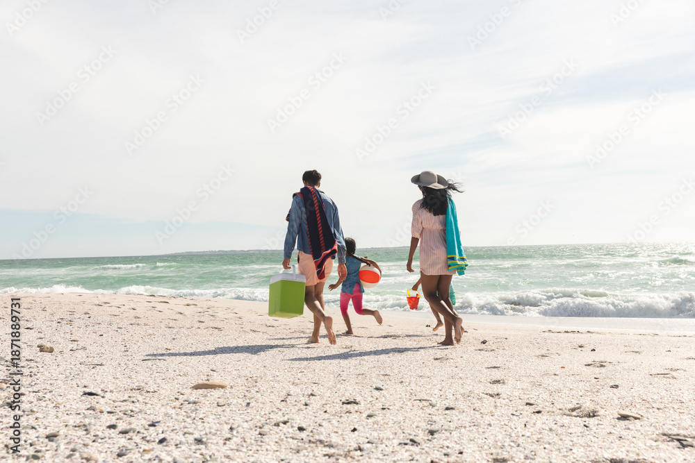 Naklejka premium Full length rear view of multiracial family walking on shore at beach during sunny day