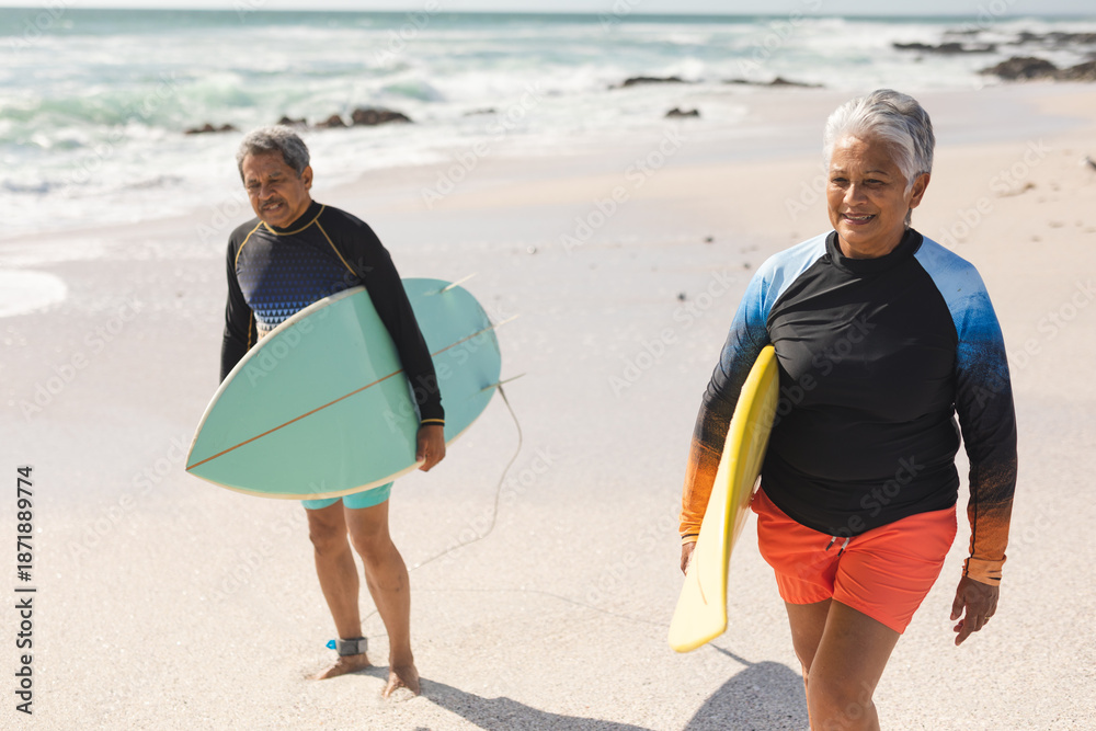 Fototapeta premium senior couple with surfboards walking at beach during sunny day