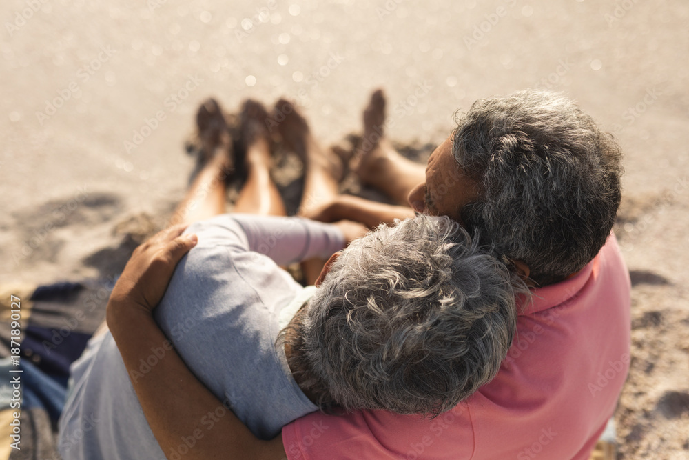 Fototapeta premium High angle view of loving multiracial senior couple enjoying sunny day at beach