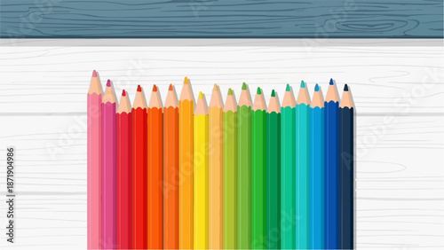 Vibrant colored pencils arranged in a rainbow spectrum on a textured white surface with a dark blue wooden texture above