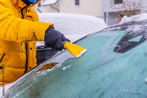 Removing snow and ice from car windshield.