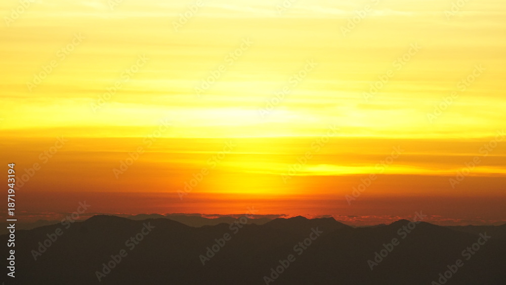 Fototapeta premium Golden sunrise over mountain silhouettes with warm sky 