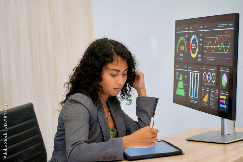 Obraz premium Mixed color businesswoman working with tablet and information graph on monitor for idea business.