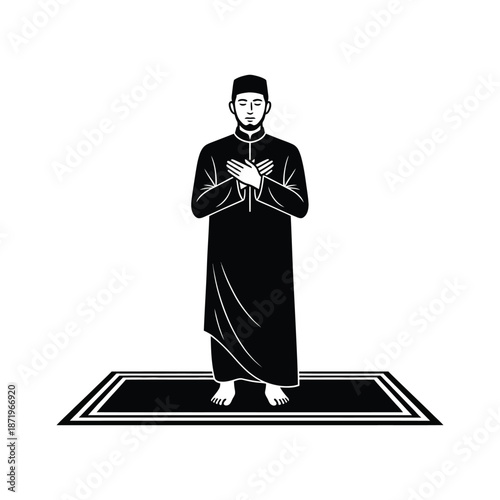 A man in traditional islamic clothing standing in prayer on a small prayer rug