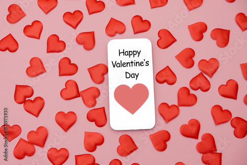 Red heart shapes scattered on a pink background with a card that reads 'Happy Valentine's Day'.