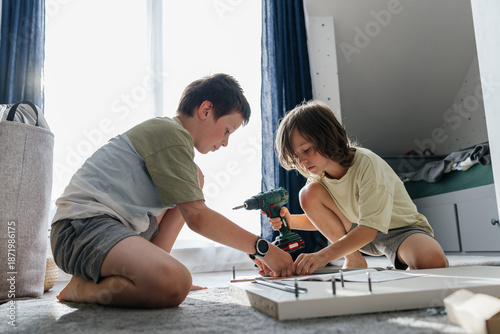 Photos Children assembling flat pack furniture using a power drill