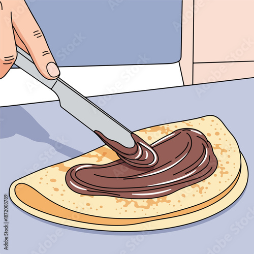 Hand applying chocolate spread to a pancake with a knife on a table with a blue surface and pink wall.