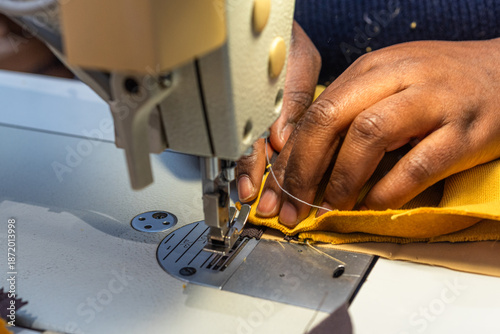 Black woman sews fabric with sewing machine