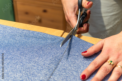 seamstress cuts a piece of fabric with scissors following a line