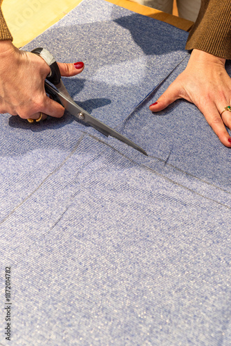 seamstress cuts a piece of fabric with scissors following a line
