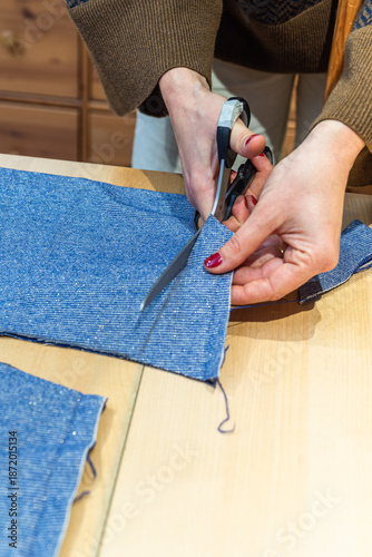 seamstress cuts a piece of fabric with scissors following a line