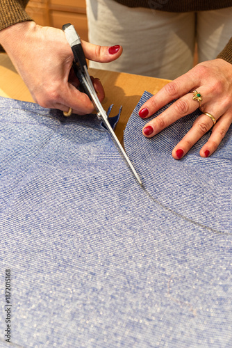 seamstress cuts a piece of fabric with scissors following a line