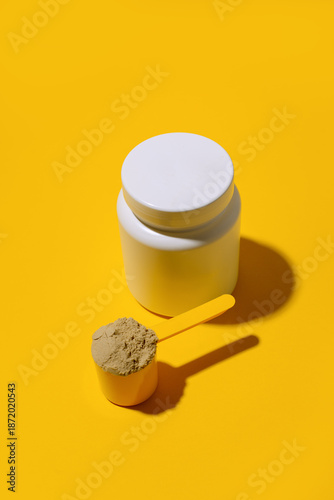 Scoop of Whey protein powder. Sports nutrition. Fitness diet and food concept - whey and soy protein shake powder, collagen on bright yellow background, copy space, banner, flyer