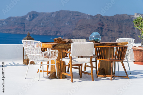 Table with chairs with white washed wall - inspiring desire to travel in Oia, Santorini, Greece