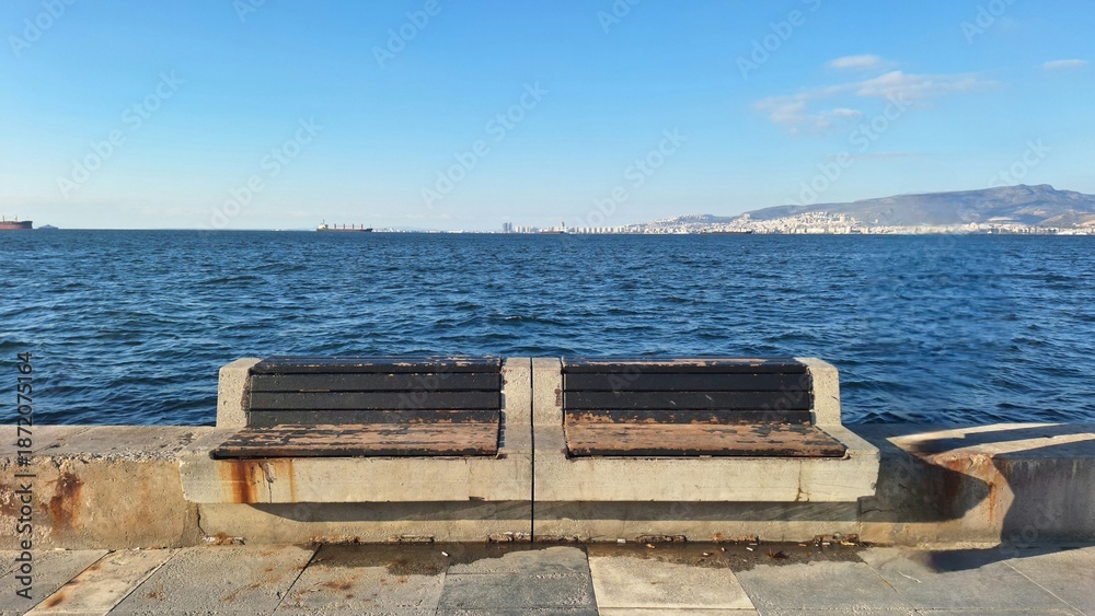 Fototapeta premium Empty concrete bench by the sea on a clear day