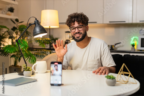 Фотография Arabian man at home records short video on smartphone speaks to camera shares news for audience