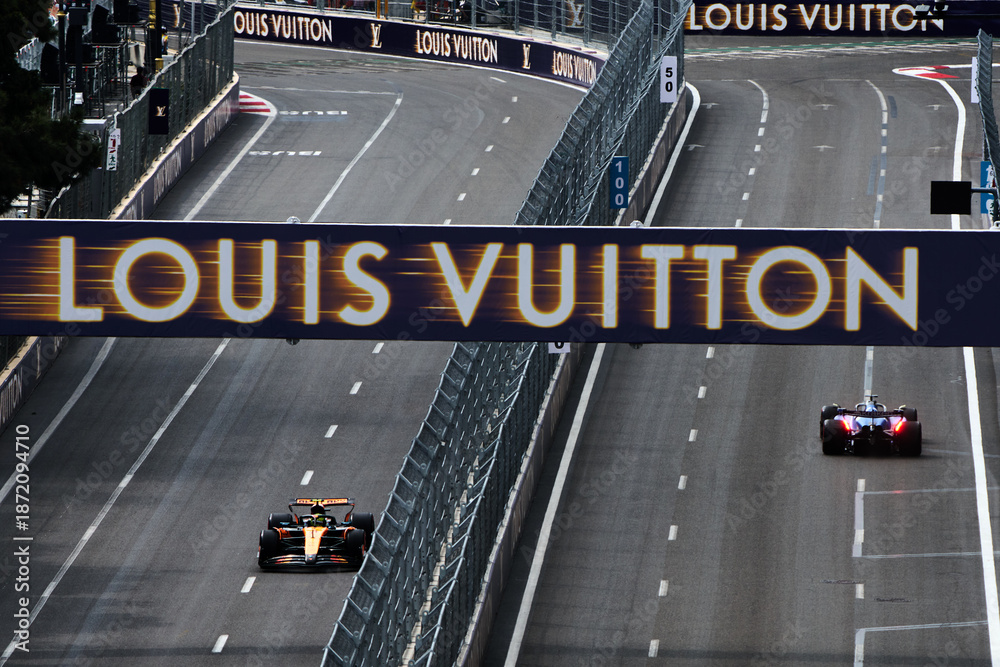 Fototapeta premium BAKU, AZERBAIJAN - SEPTEMBER 19, 2025: A McLaren F1 car and a Williams Racing car on the track under a prominent Louis Vuitton sponsorship banner during the Formula 1