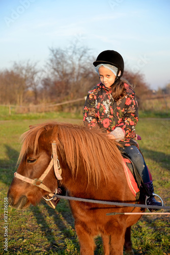Little girl sits astride a pony