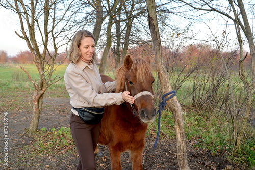 A young woman stands next to an outdoor pony