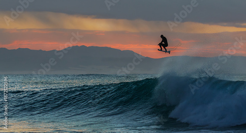 Silhouette of an airborne  surfer at sunrise
