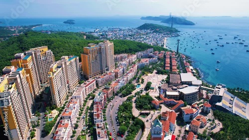 Wallpaper Mural Phu Quoc, Sunset Town, Vietnam. 4k high-quality drone footage, showcasing colorful buildings, blue skies, a watch tower, a kissing bridge, turquoise clear waters, green forest, and golden sand Torontodigital.ca