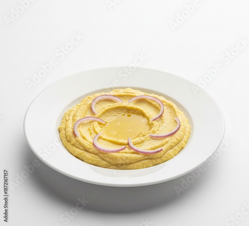 Top view of Greek fava yellow split pea puree decorated with red onion rings and olive oil on white background.