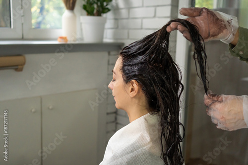 Gloved hands massage and distribute the product or dye through the woman's wet hair. beauty salon home care health concept