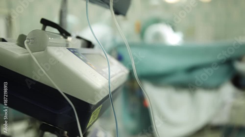 Timelapse shot of anesthesia equipment in a hospital operating room with surgical procedure blurred in background